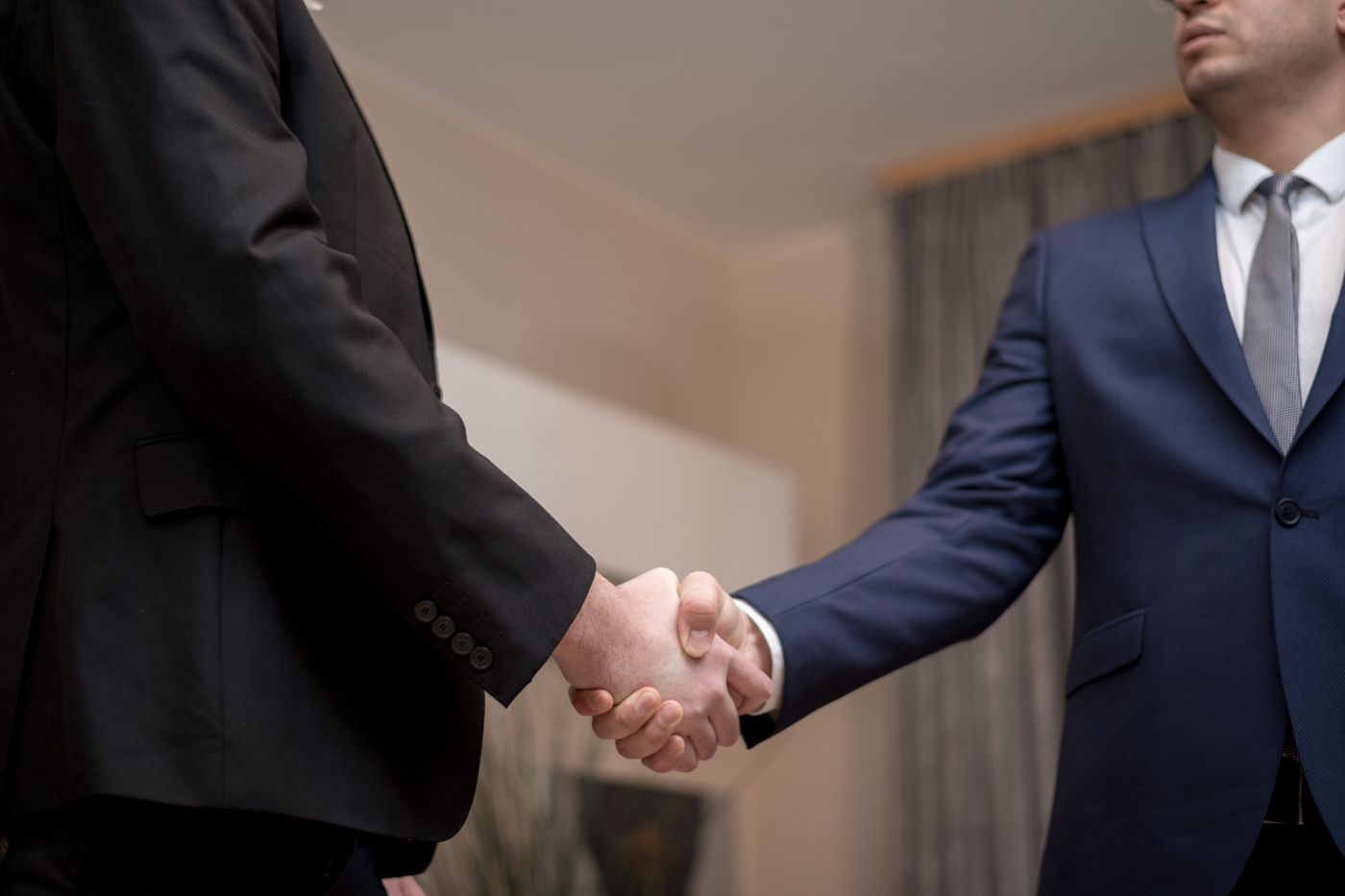 Takım elbiseli iki iş insanının el sıkışması – E-Ticaret Sitesi Yapan Firmalar Nasıl Değerlendirilir? 10 Soru